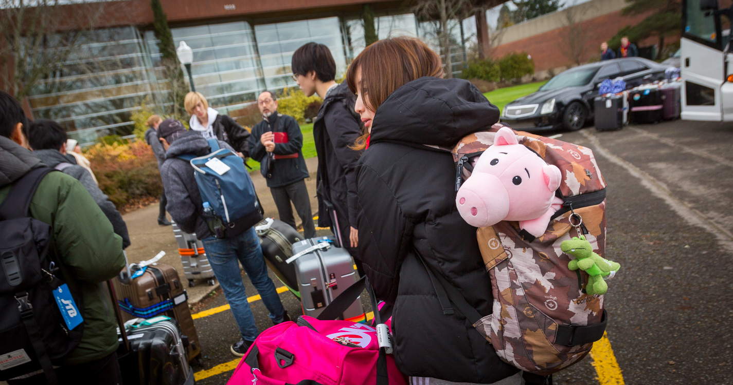 A pink stuffed animal pig sticking out of a student's backpack