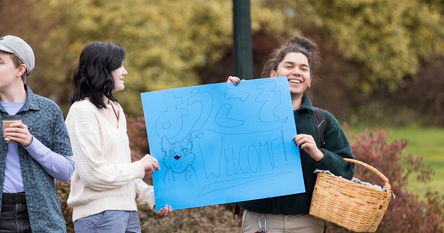 two students holding a blue welcome sign