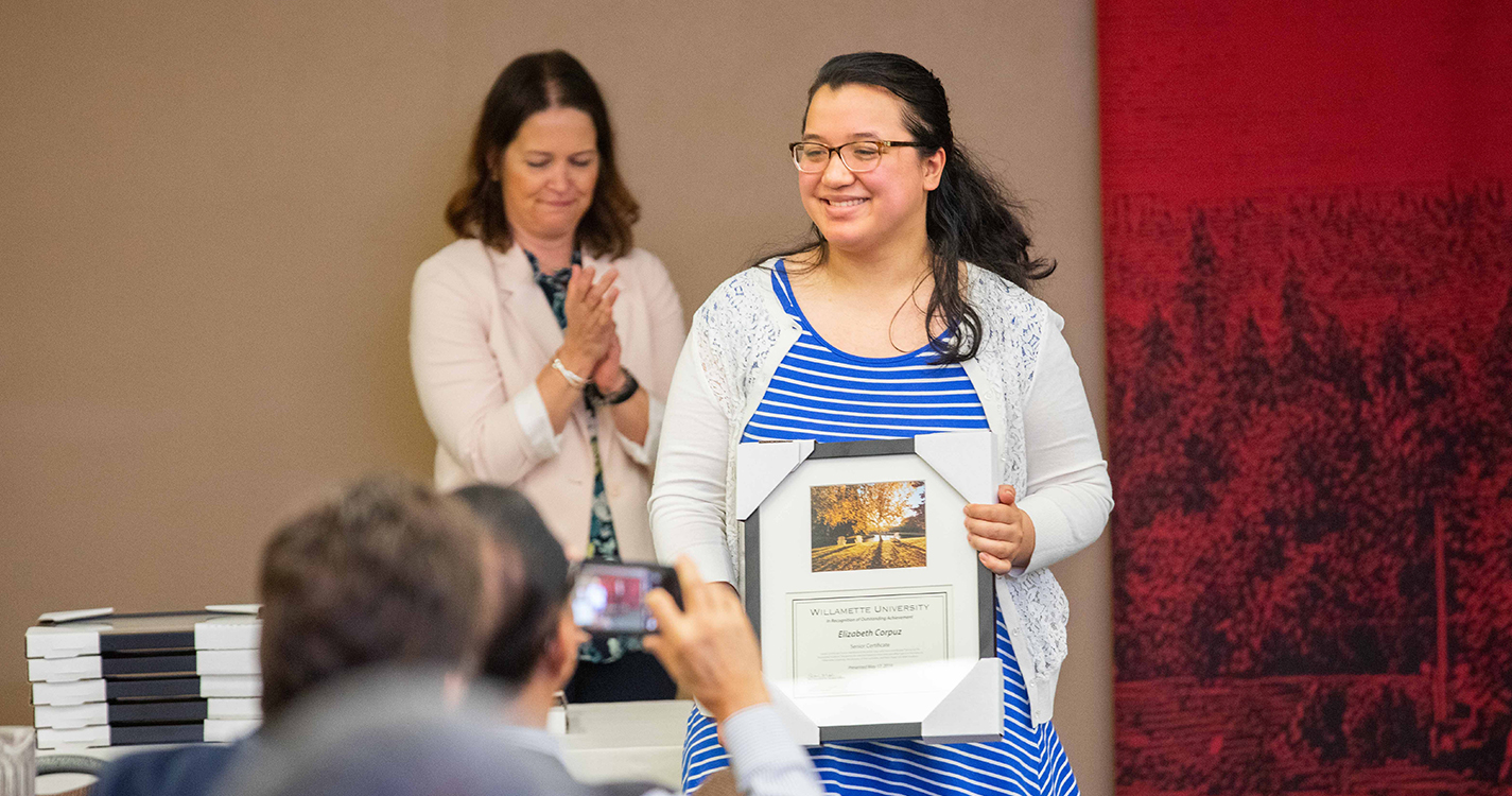 Smiling student holds an award plaque