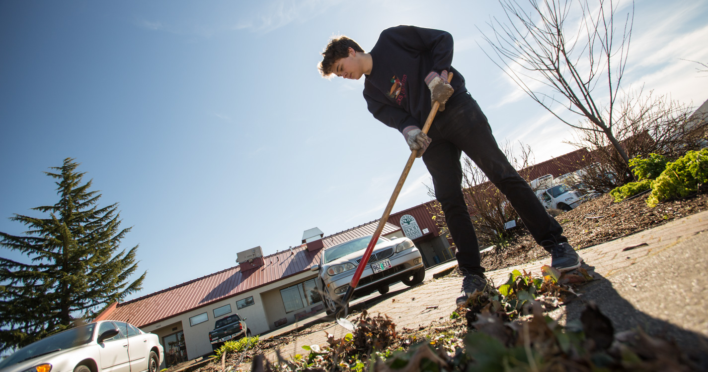 Student tills the soil with a rake as part of Willamette’s Global Day of Service.