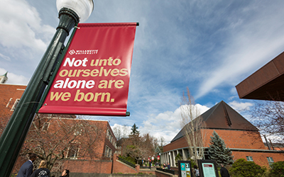 light post with banner saying "Willamette University Not unto ourselves alone are we born." with Roger's Music Hall in background