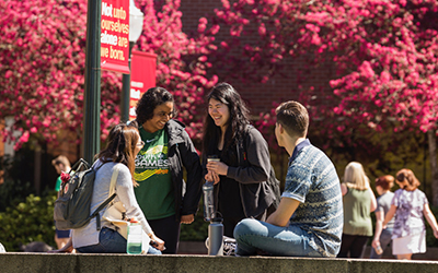 four students converse in Jackson Plaza in spring