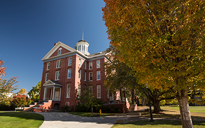 Waller Hall on a sunny autumn day with orange-yellow tree in foreground 